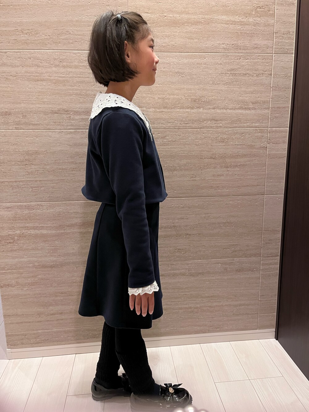 ブラック系のワンピース、ブラック系のノーカラージャケット、ブラック系のローファーを着用したキッズの冬コーディネートの2枚目の写真