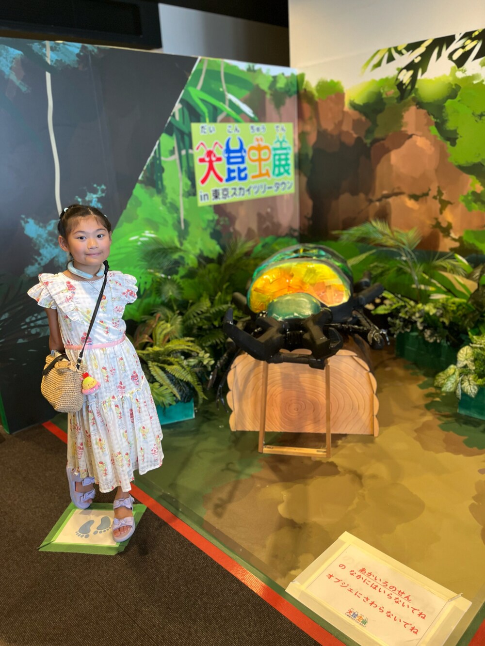 ホワイト系のワンピース、ベージュ系のかごバッグ、パープル系のサンダルを着用したキッズの夏コーディネートの2枚目の写真