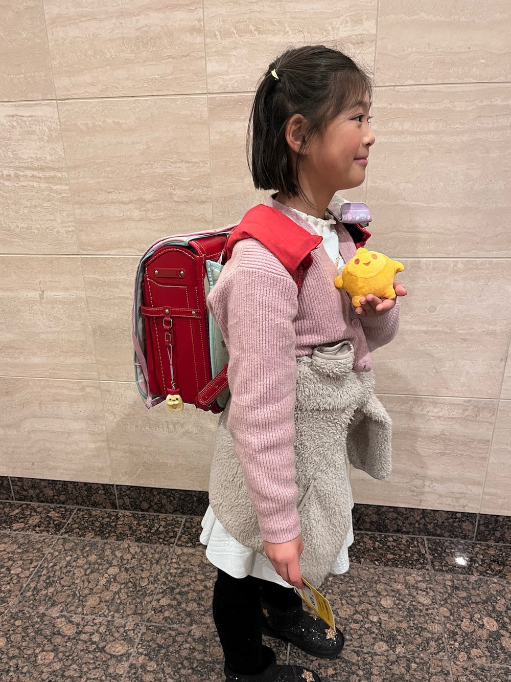 ピンク系のカーディガン/ボレロ、ベージュ系のノーカラージャケット、シルバー系のワンピースを着用したキッズの冬コーディネートの2枚目の写真