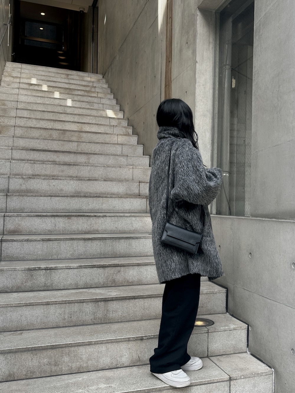 グレー系のステンカラーコートを着用したレディースの冬コーディネートの4枚目の写真