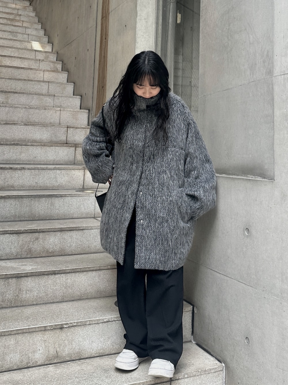 グレー系のステンカラーコートを着用したレディースの冬コーディネートの3枚目の写真