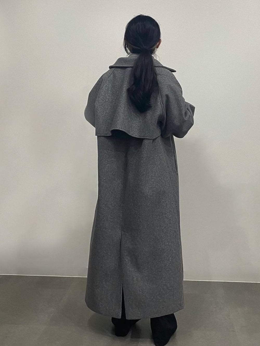 グレー系のニット/セーター、グレー系のステンカラーコート、ブラック系のスラックスを着用したレディースの秋コーディネートの2枚目の写真