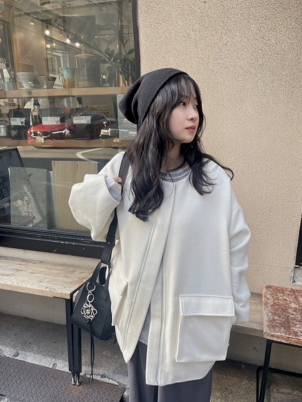 ホワイト系のブルゾン、ブラック系のハンドバッグ、ブラック系のニットキャップ/ビーニーを着用したレディースの冬コーディネートの2枚目の写真