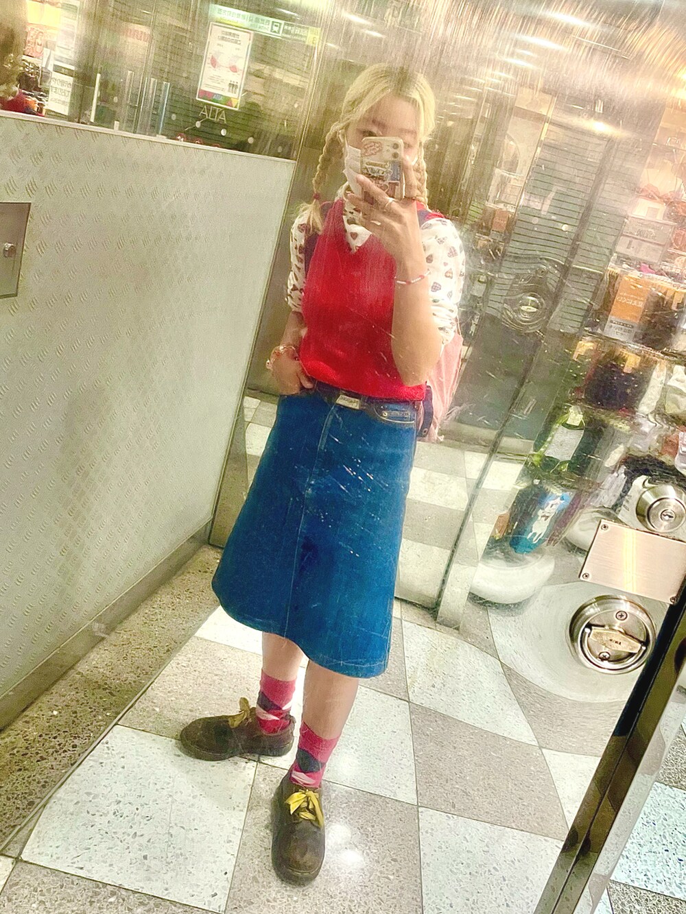 レッド系のベスト、ブルー系のデニムスカート、ホワイト系のその他トップスを着用したレディースの秋コーディネートの2枚目の写真