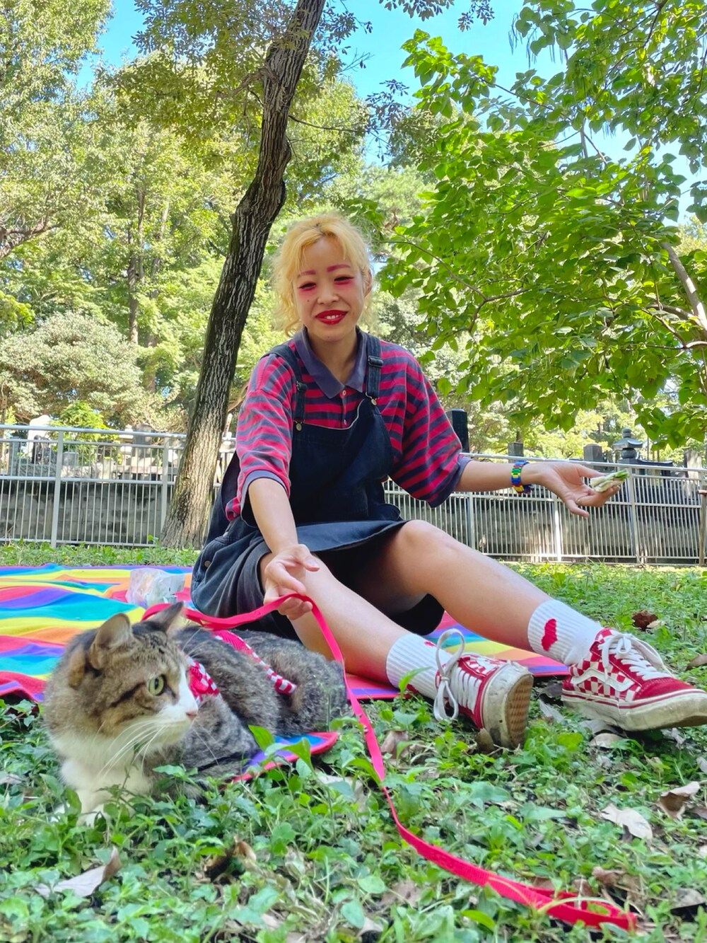 ブラック系のサロペット/オーバーオール、レッド系のポロシャツ、レッド系のスニーカーを着用したレディースの秋コーディネートの2枚目の写真