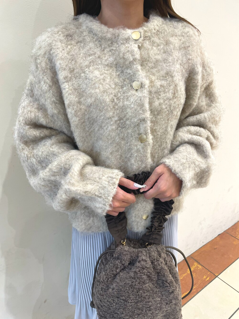 ベージュ系のカーディガン/ボレロ、グレー系のスカート、ホワイト系のブーツを着用したレディースの秋コーディネートの2枚目の写真