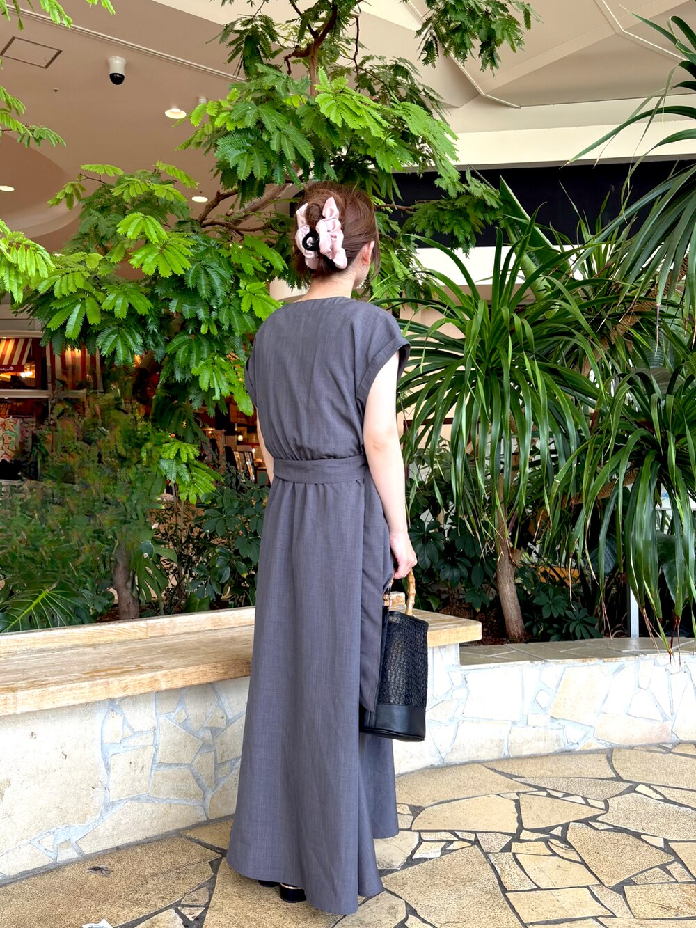 グレー系のワンピース、ブラック系のハンドバッグ、ホワイト系のネックレスを着用したレディースの夏コーディネートの3枚目の写真