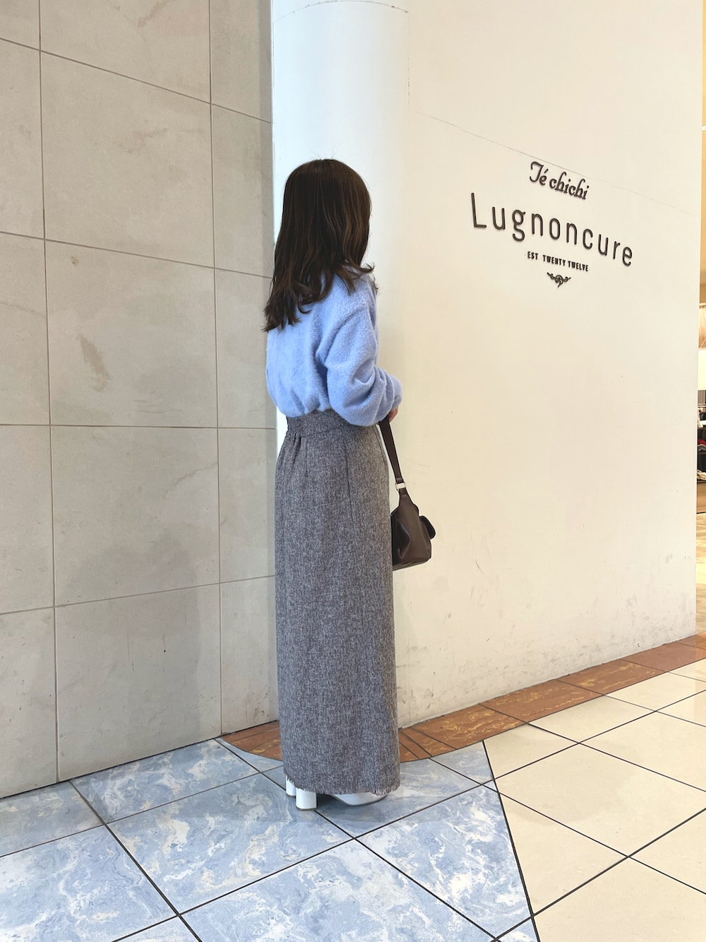 ブルー系のニット/セーター、ブラウン系のスカート、ブラウン系のハンドバッグを着用したレディースの秋コーディネートの2枚目の写真