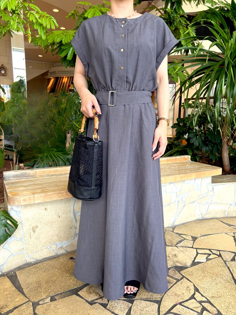 グレー系のワンピース、ブラック系のハンドバッグ、ホワイト系のネックレスを着用したレディースの夏コーディネートの4枚目の写真