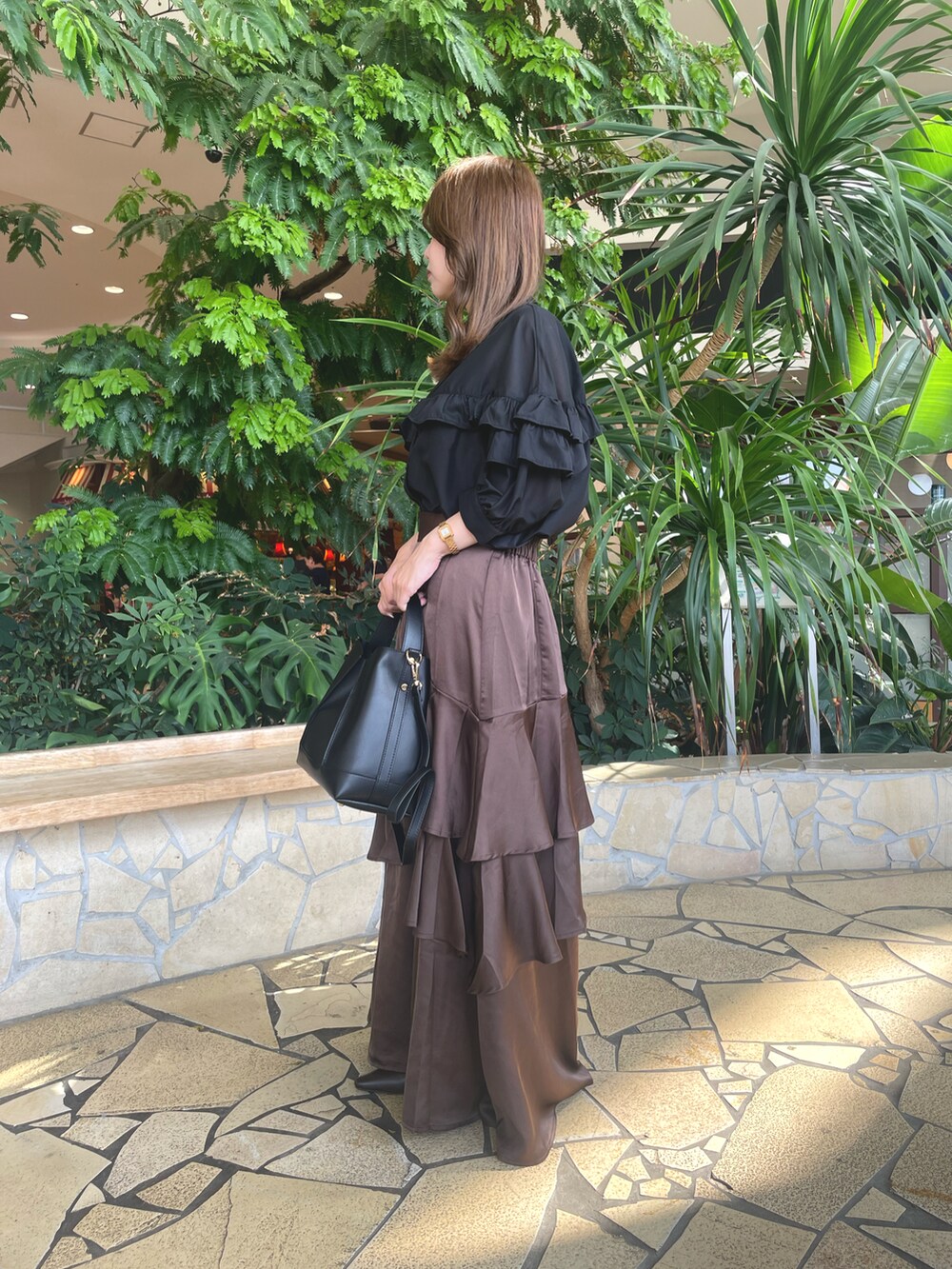 ブラウン系のスカート、ブラック系のハンドバッグ、ブラック系のシャツ/ブラウスを着用したレディースの秋コーディネートの2枚目の写真