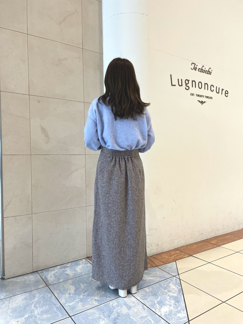 ブルー系のニット/セーター、ブラウン系のスカート、ブラウン系のハンドバッグを着用したレディースの秋コーディネートの3枚目の写真