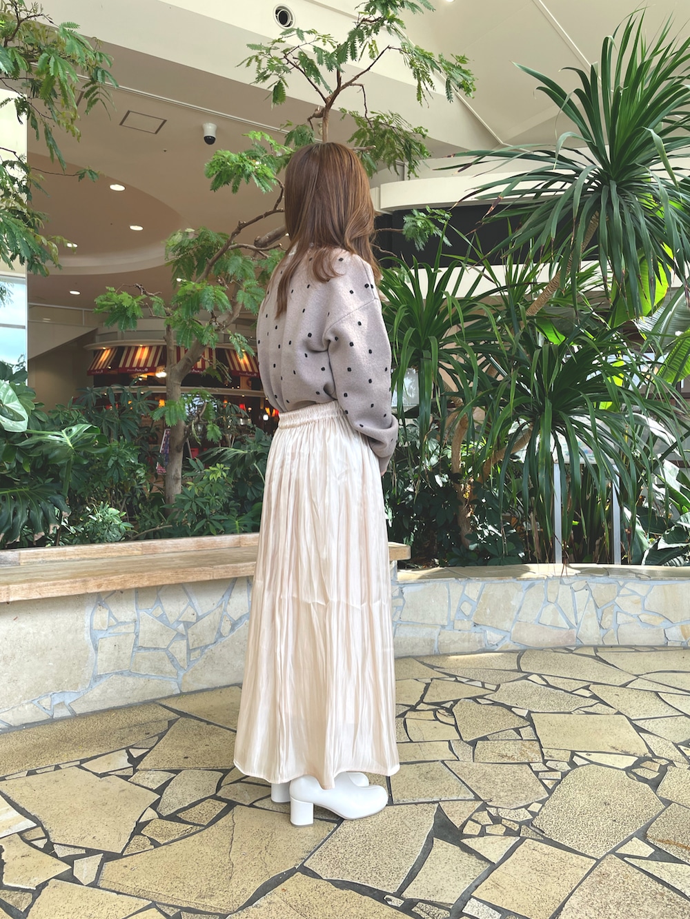 ベージュ系のスカート、ブラウン系のニット/セーター、ホワイト系のブーツを着用したレディースの秋コーディネートの2枚目の写真