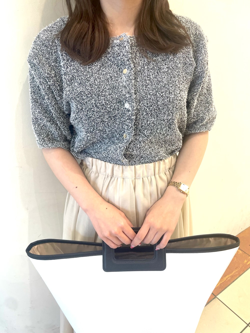 グレー系のカーディガン/ボレロ、ホワイト系のスカート、ホワイト系のハンドバッグを着用したレディースの春コーディネートの3枚目の写真