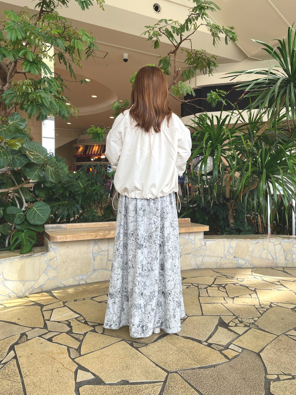 ベージュ系のニット/セーター、ホワイト系のブルゾン、グレー系のスカートを着用したレディースの秋コーディネートの4枚目の写真