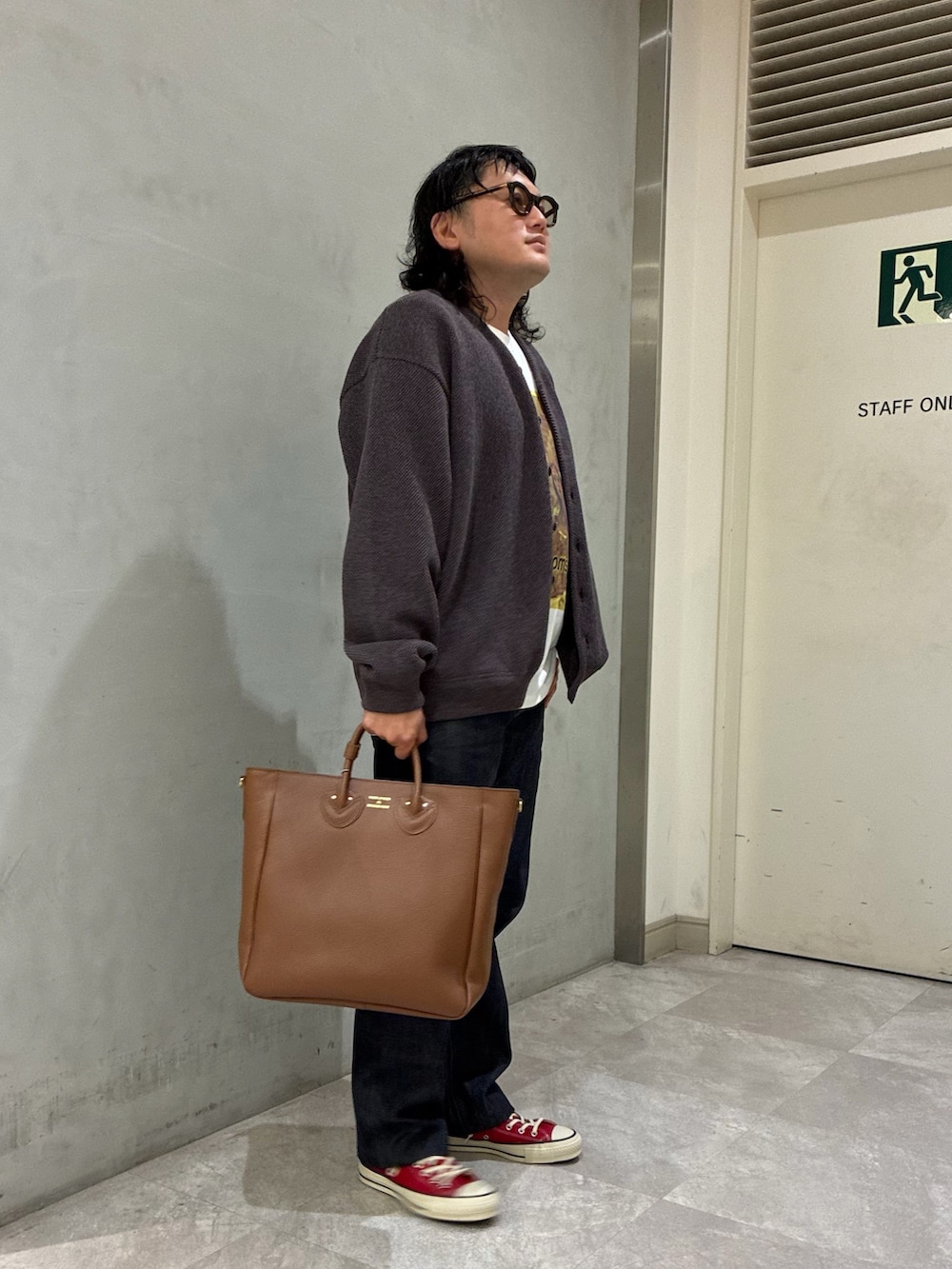 ブラウン系のカーディガン/ボレロ、ブルー系のデニムパンツ、ブラウン系のトートバッグを着用したメンズの秋コーディネートの2枚目の写真