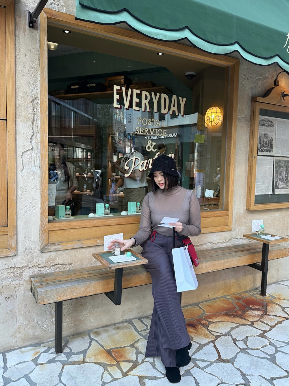 ベージュ系のノーカラージャケット、パープル系のチノパンツ、ブラック系の帽子を着用したレディースの秋コーディネートの2枚目の写真