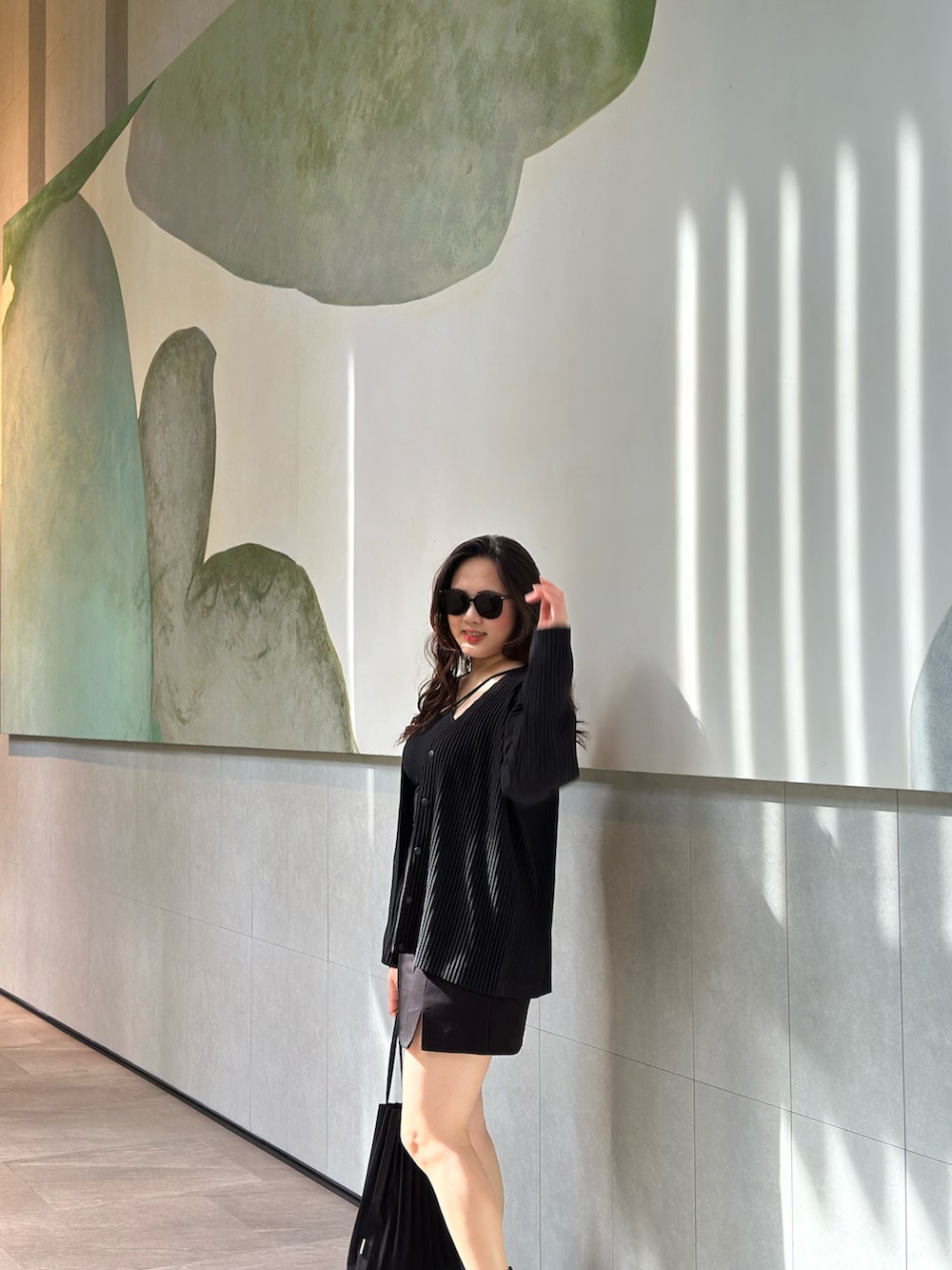 ブラック系のノーカラージャケット、ブラック系のバッグ、ブラック系のブーツを着用したレディースの春コーディネートの2枚目の写真