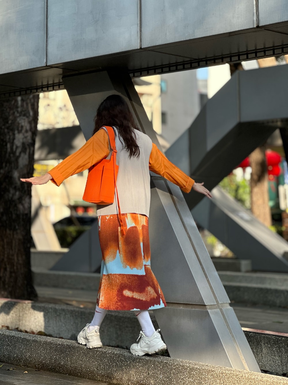 ホワイト系のシューズ、オレンジ系のジャンパースカートを着用したレディースの冬コーディネートの3枚目の写真