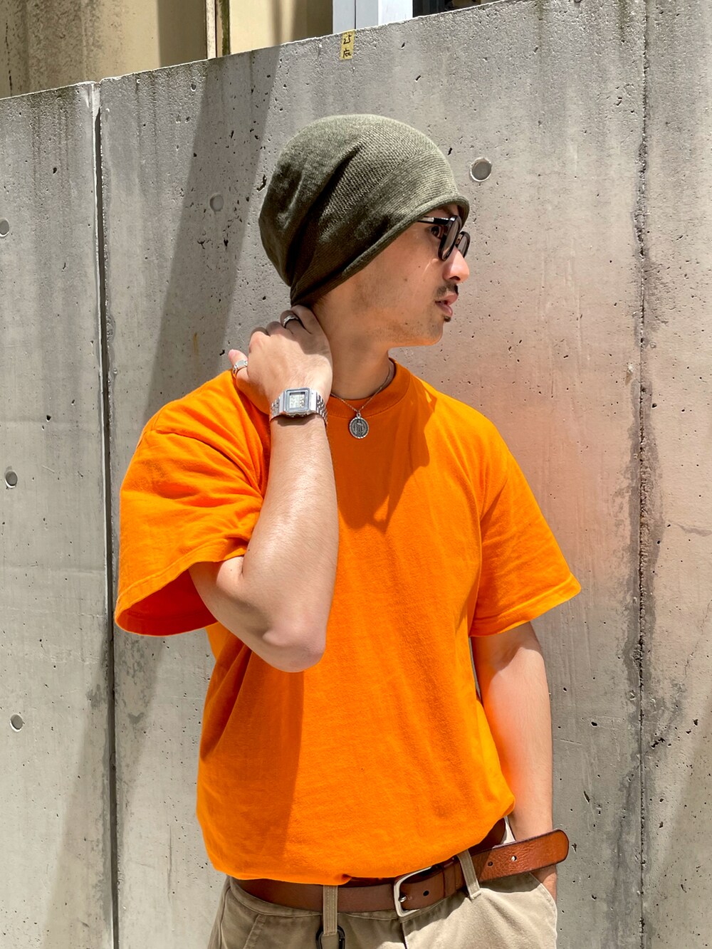 オレンジ系のTシャツ/カットソー、ベージュ系のチノパンツ、ブラウン系のシューズを着用したメンズの夏コーディネートの2枚目の写真