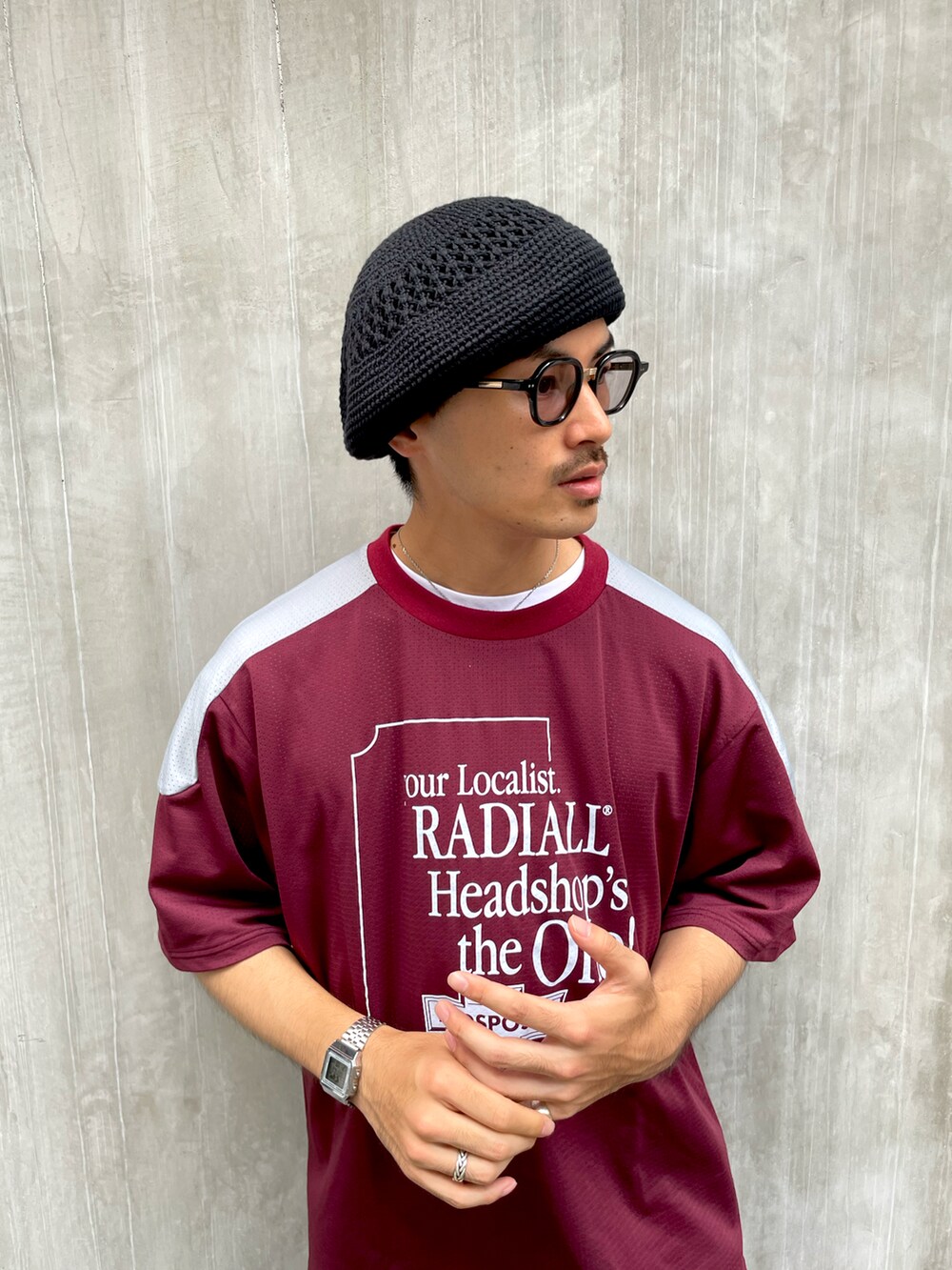 レッド系のTシャツ/カットソー、ブラウン系のチノパンツ、ブラック系のスニーカーを着用したメンズの夏コーディネートの2枚目の写真