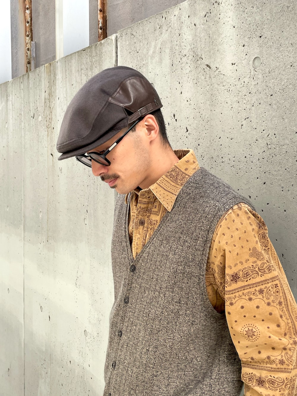 グレー系のスラックス、ベージュ系のベスト、ブラック系のローファーを着用したメンズの秋コーディネートの2枚目の写真