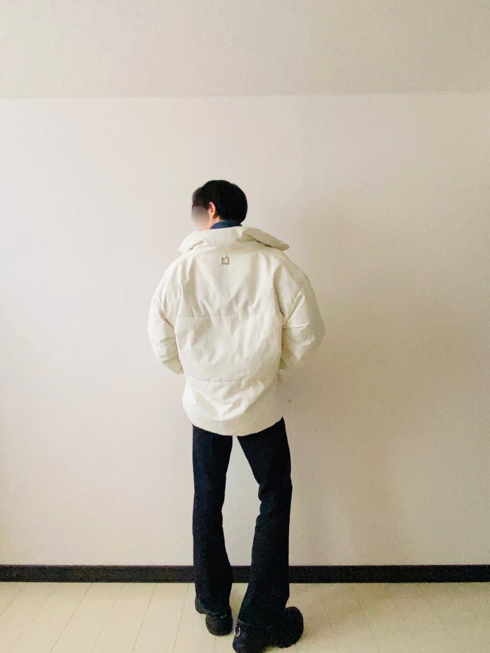 ホワイト系のダウンジャケット/コート、グリーン系のニット/セーター、ブルー系のデニムパンツを着用したメンズの冬コーディネートの2枚目の写真