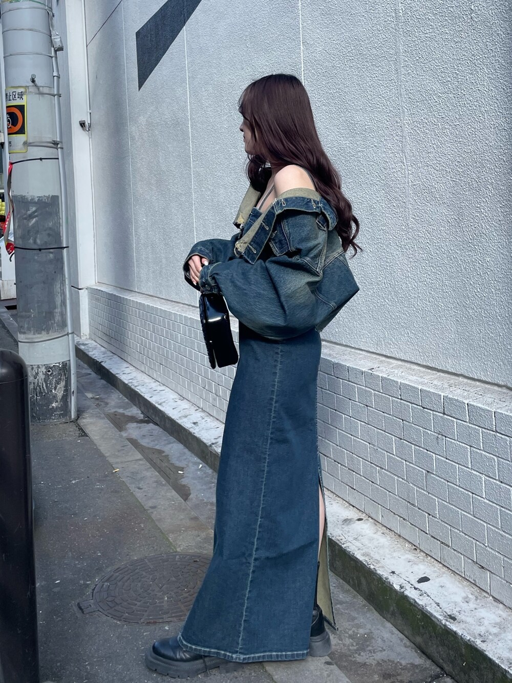 ブラック系のショルダーバッグ、ブルー系のワンピース、ブルー系のデニムジャケットを着用したレディースの冬コーディネートの2枚目の写真