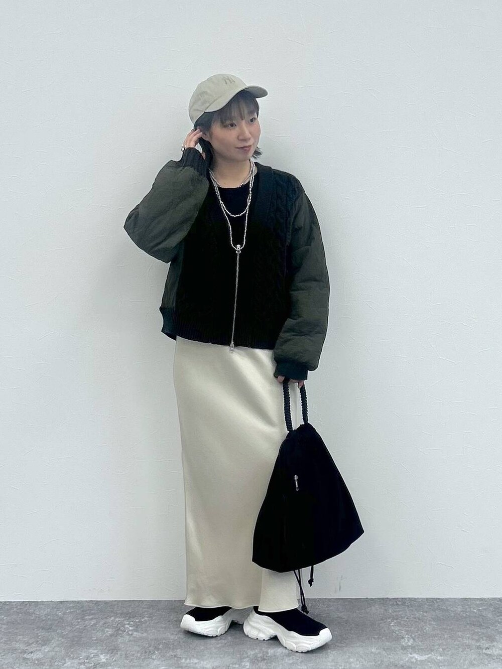 ホワイト系のスカート、グレー系のカーディガン/ボレロ、ブラック系のブーツを着用したレディースの秋コーディネートの3枚目の写真