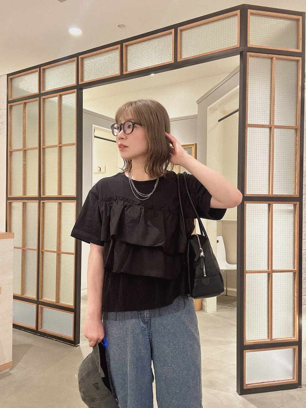 ブラック系のボストンバッグ、ブルー系のデニムパンツ、ブラック系のサンダルを着用したレディースの春コーディネートの2枚目の写真