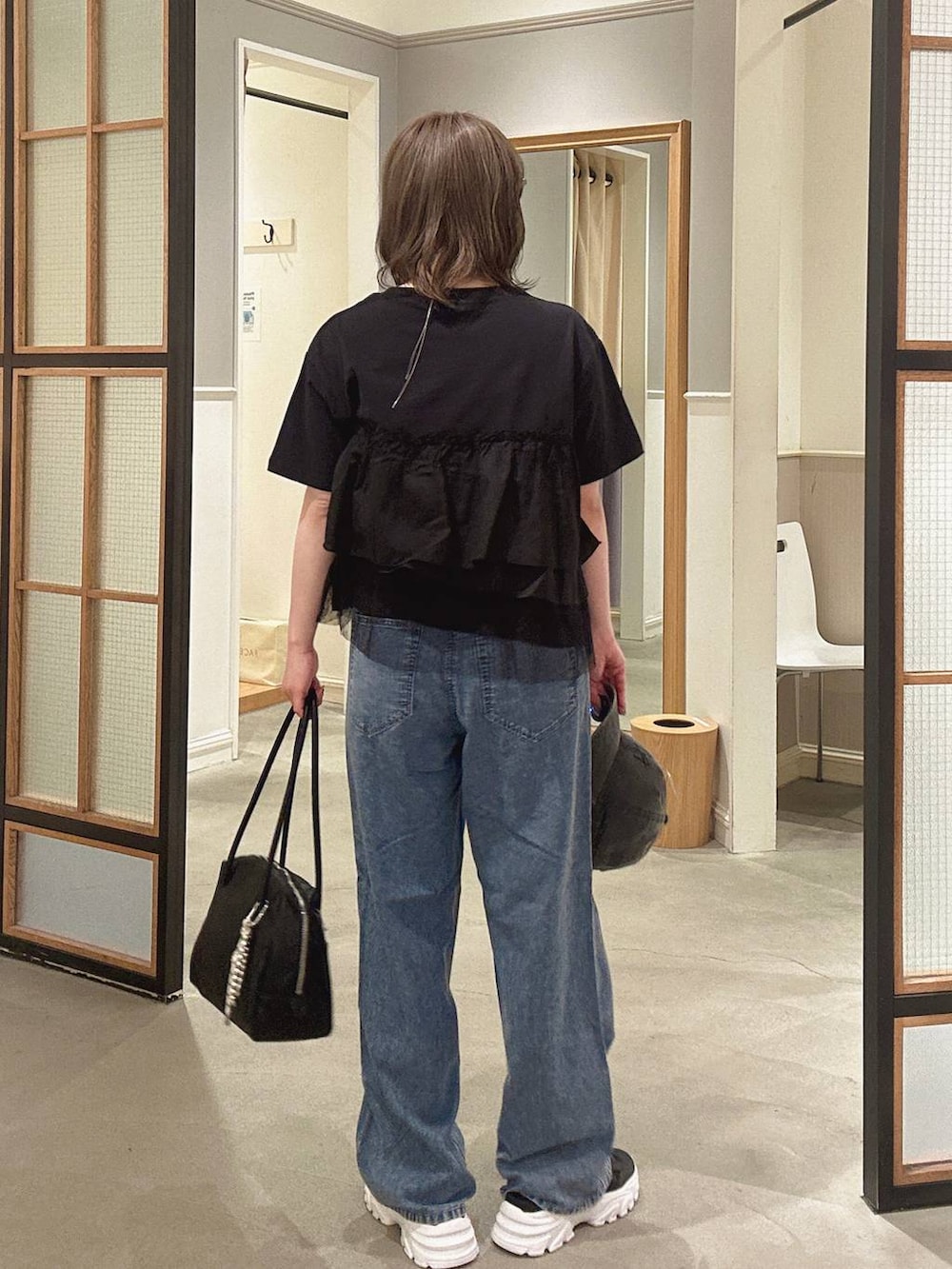 ブラック系のボストンバッグ、ブルー系のデニムパンツ、ブラック系のサンダルを着用したレディースの春コーディネートの7枚目の写真