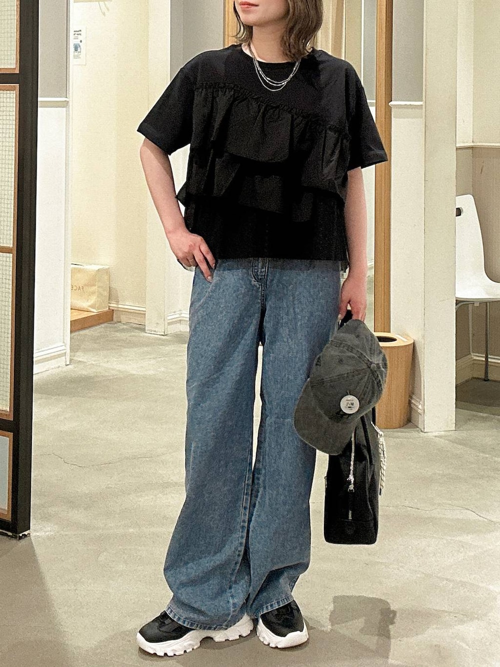 ブラック系のボストンバッグ、ブルー系のデニムパンツ、ブラック系のサンダルを着用したレディースの春コーディネートの5枚目の写真