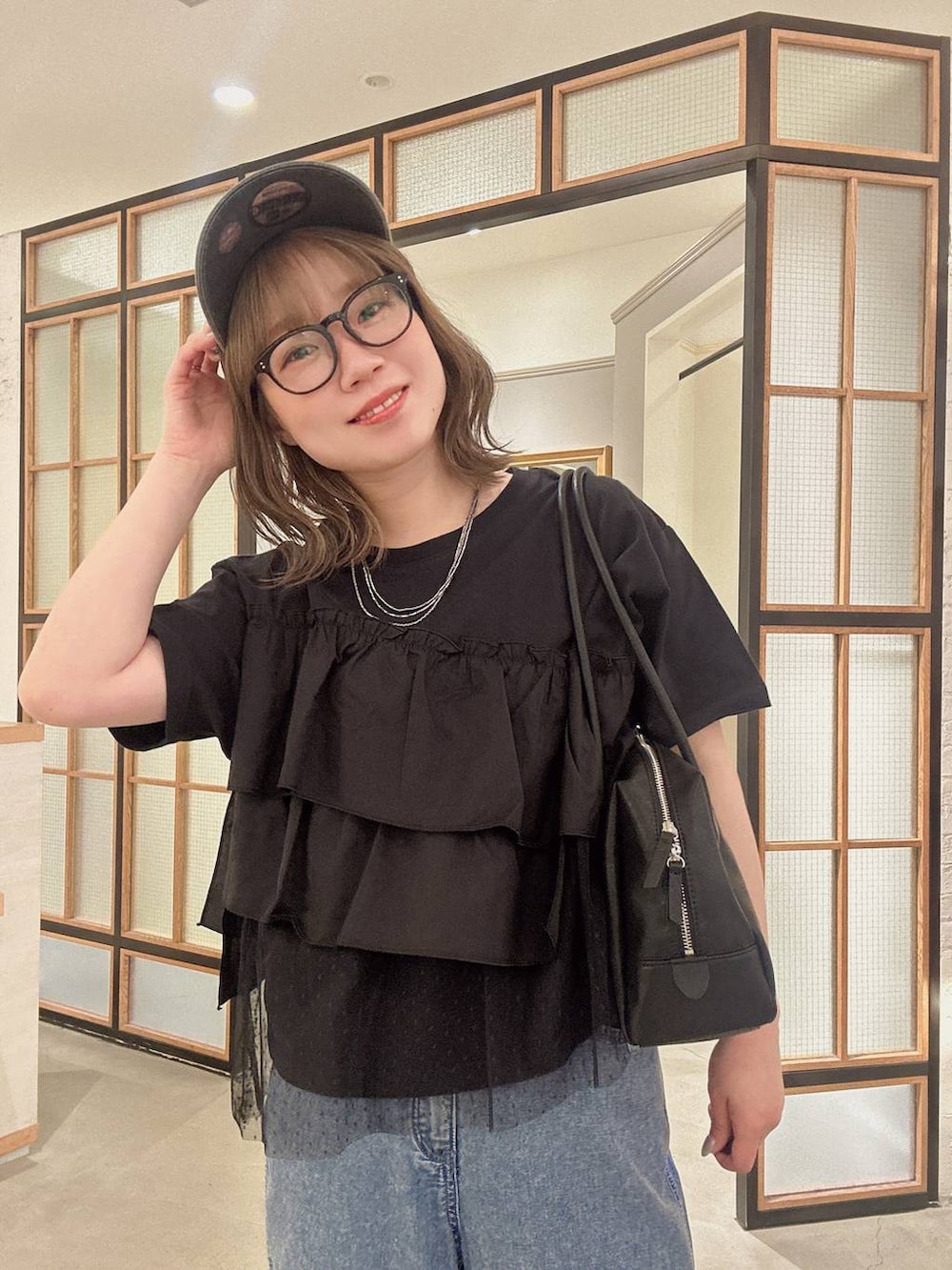 ブラック系のボストンバッグ、ブルー系のデニムパンツ、ブラック系のサンダルを着用したレディースの春コーディネートの3枚目の写真