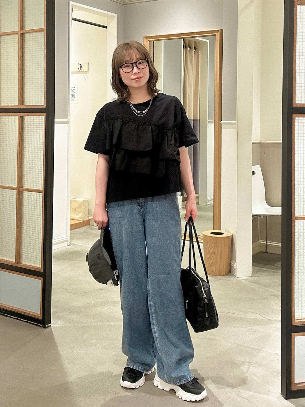 ブラック系のボストンバッグ、ブルー系のデニムパンツ、ブラック系のサンダルを着用したレディースの春コーディネートの4枚目の写真