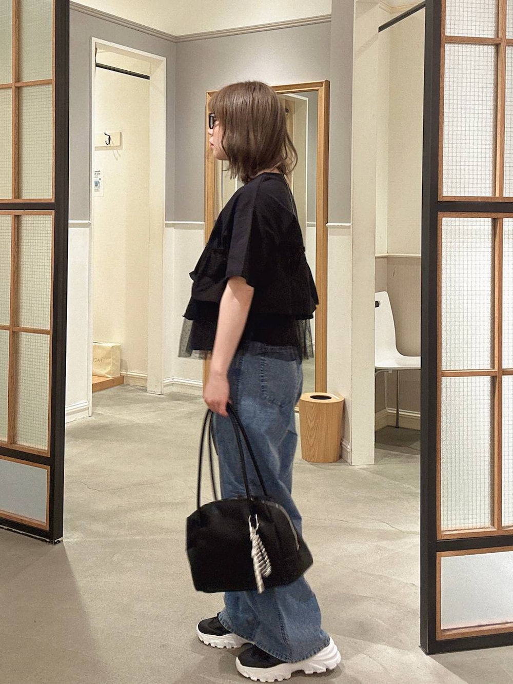 ブラック系のボストンバッグ、ブルー系のデニムパンツ、ブラック系のサンダルを着用したレディースの春コーディネートの6枚目の写真