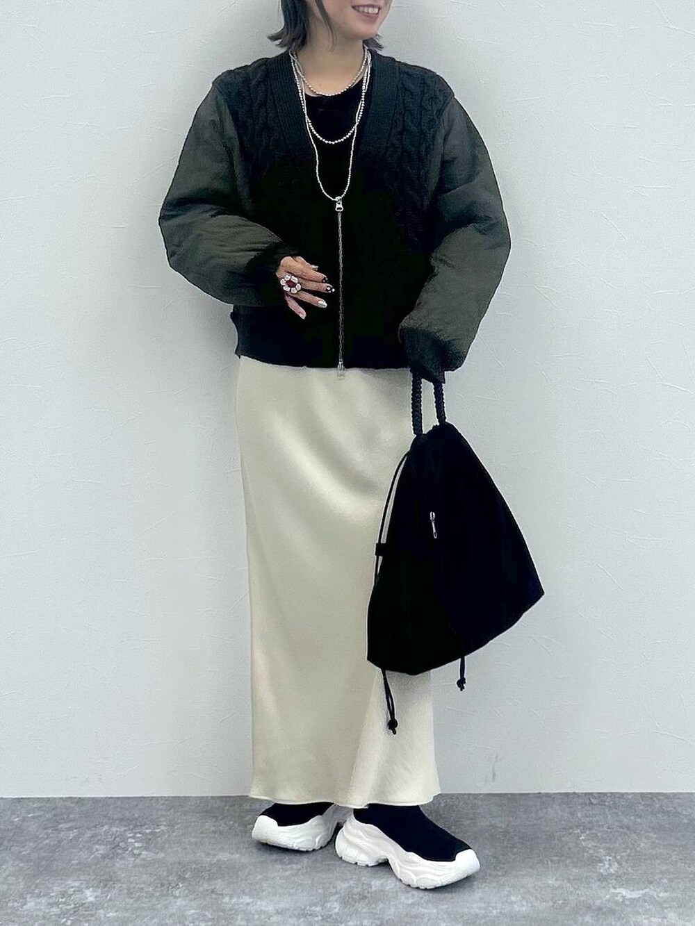 ホワイト系のスカート、グレー系のカーディガン/ボレロ、ブラック系のブーツを着用したレディースの秋コーディネートの4枚目の写真