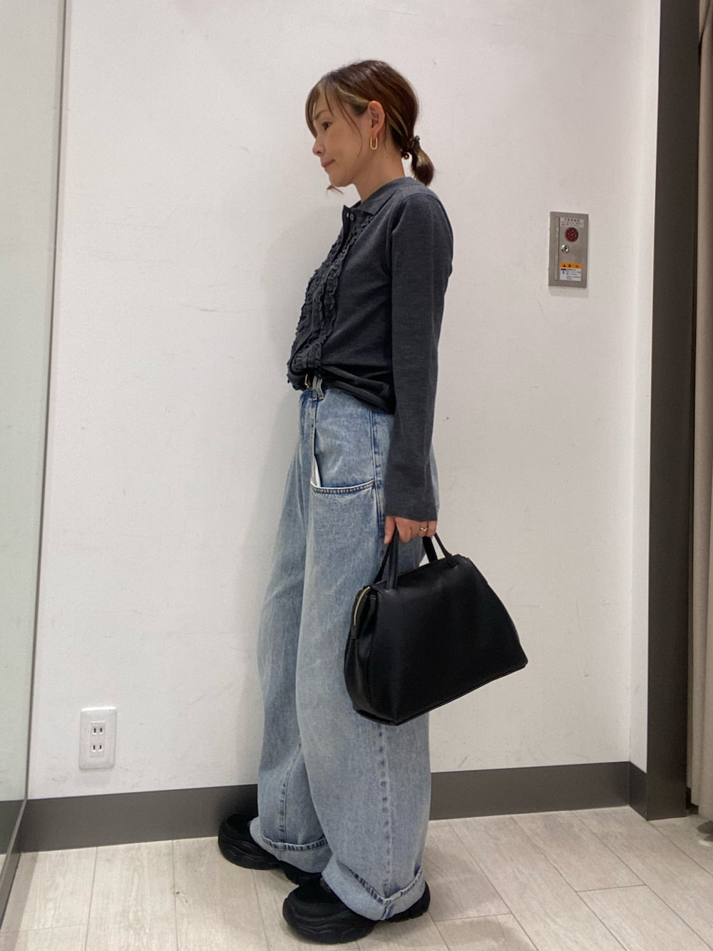 グレー系のニット/セーター、ブルー系のデニムパンツ、ブラック系のボストンバッグを着用したレディースの秋コーディネートの2枚目の写真