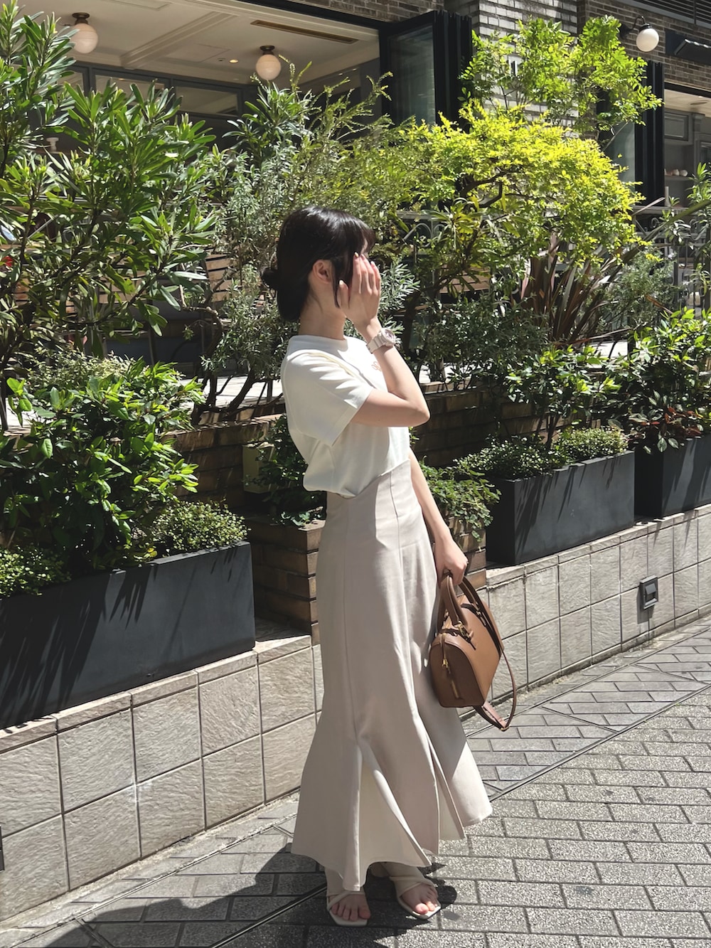 ホワイト系のTシャツ/カットソー、ブラウン系のスカート、ベージュ系のサンダルを着用したレディースの春コーディネートの2枚目の写真
