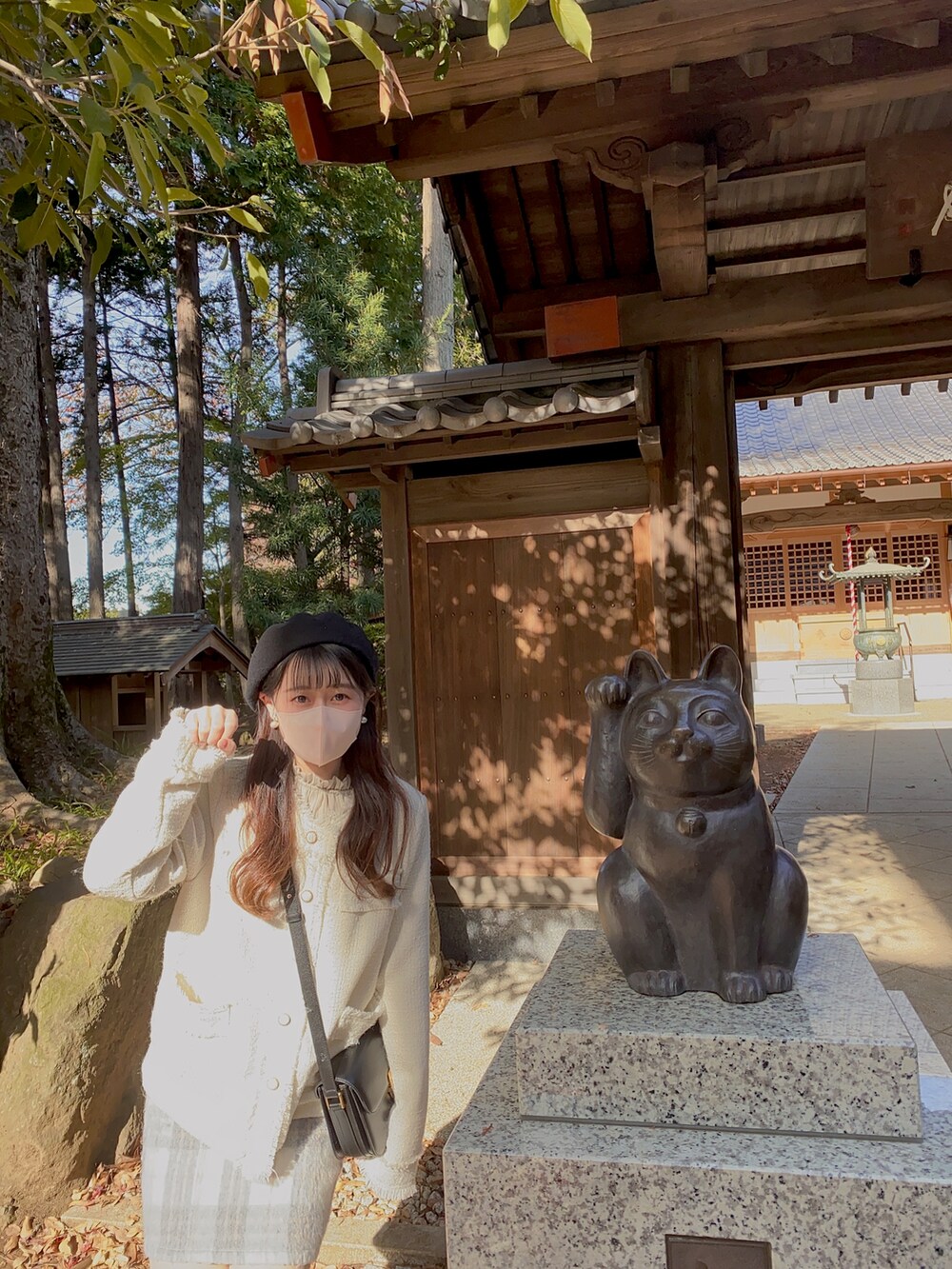 グレー系のスカート、ホワイト系のノーカラージャケット、ブラック系のショルダーバッグを着用したレディースの秋コーディネートの2枚目の写真