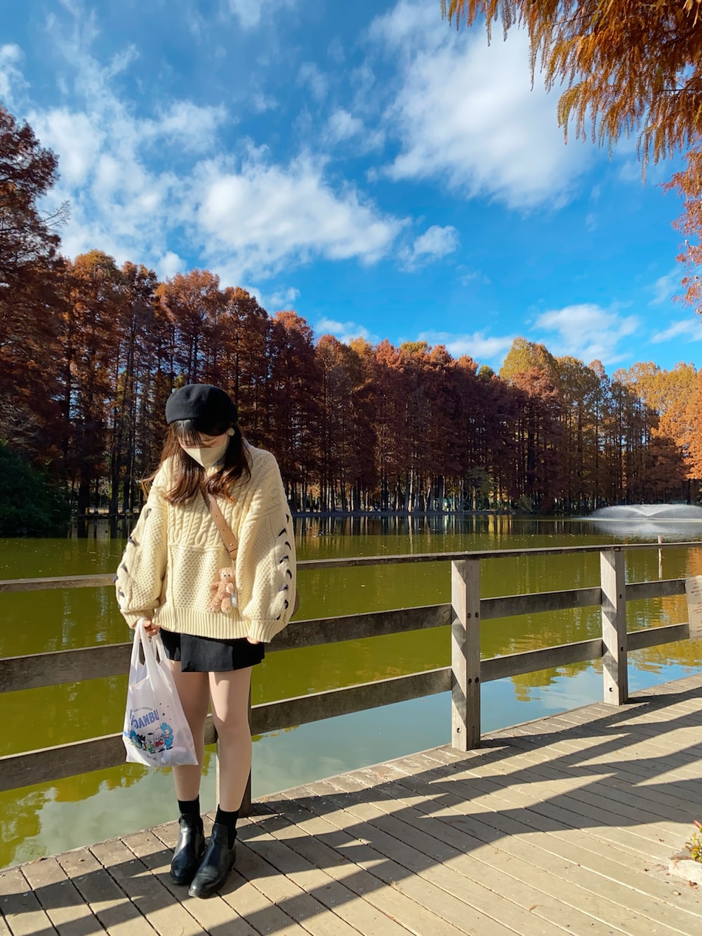 ホワイト系のニット/セーター、ブラック系のブーツ、ブラウン系のショルダーバッグを着用したレディースの冬コーディネートの3枚目の写真