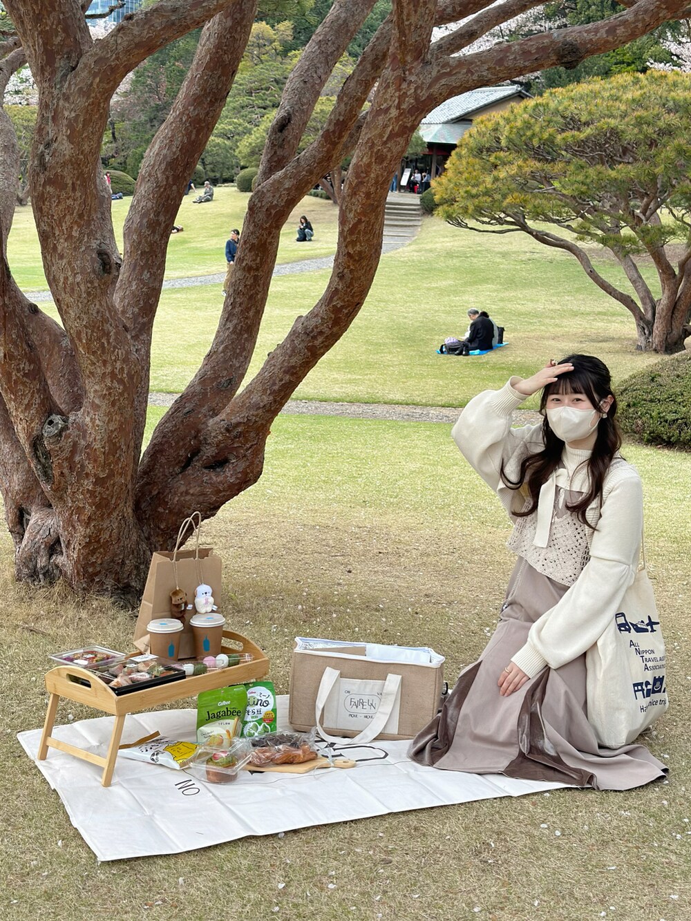 ホワイト系のトップス、ホワイト系のカーディガン/ボレロ、ブラウン系のドレスを着用したレディースの春コーディネートの3枚目の写真