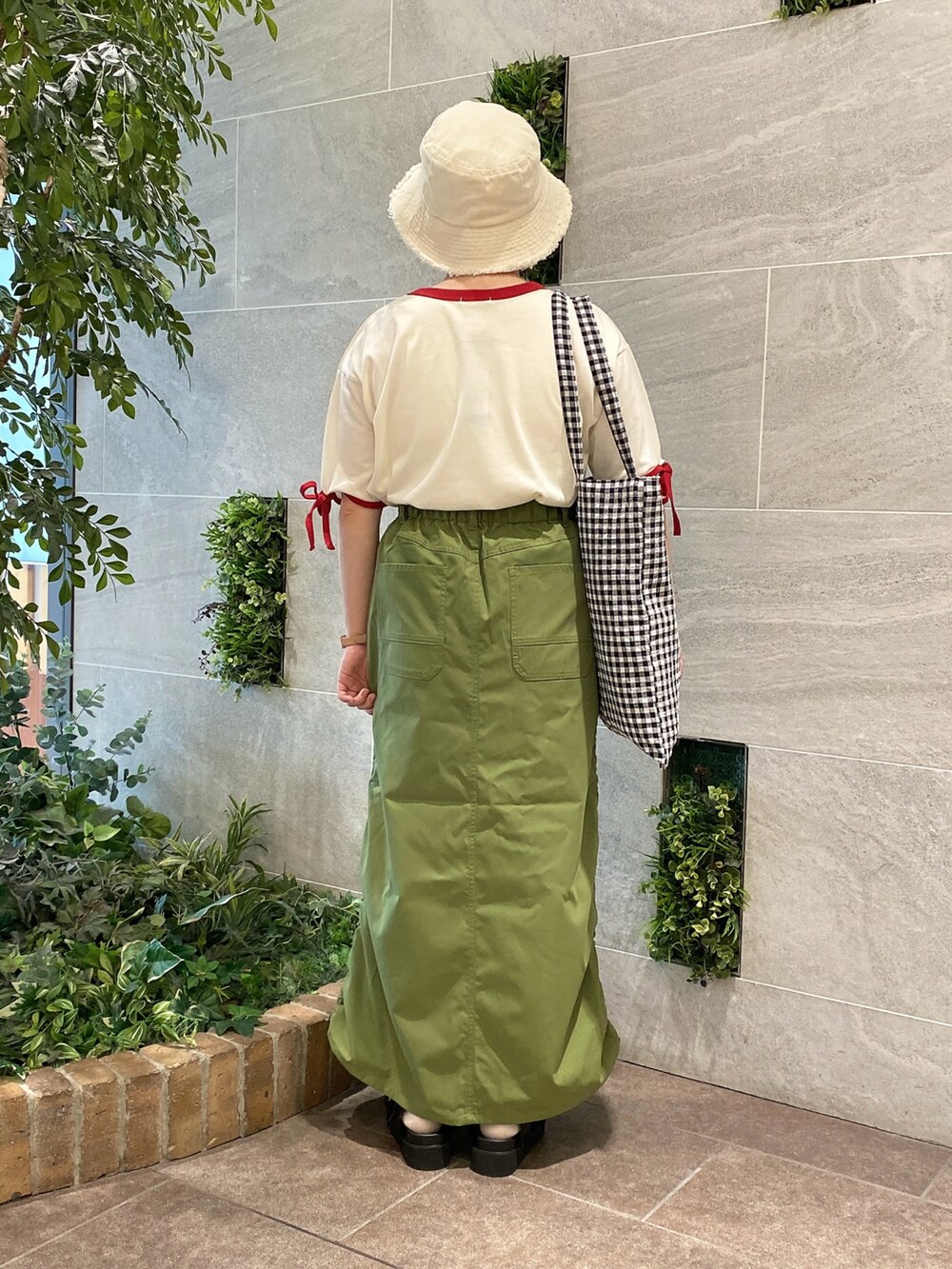 ホワイト系のTシャツ/カットソー、グリーン系のスカート、ブラック系のハンドバッグを着用したレディースの春コーディネートの2枚目の写真