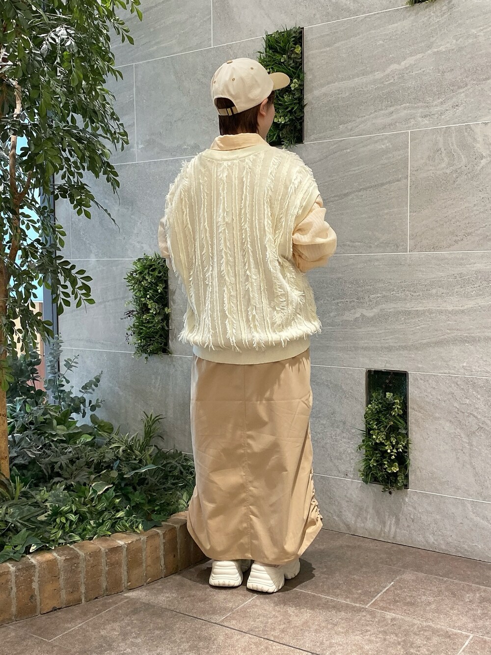 ホワイト系のベスト、オレンジ系のシャツ/ブラウス、ベージュ系のスカートを着用したレディースの春コーディネートの3枚目の写真