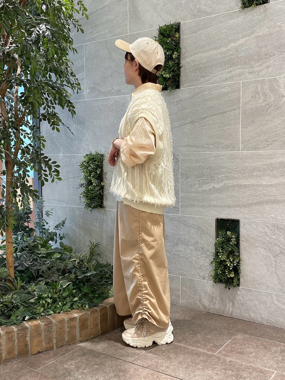 ホワイト系のベスト、オレンジ系のシャツ/ブラウス、ベージュ系のスカートを着用したレディースの春コーディネートの2枚目の写真