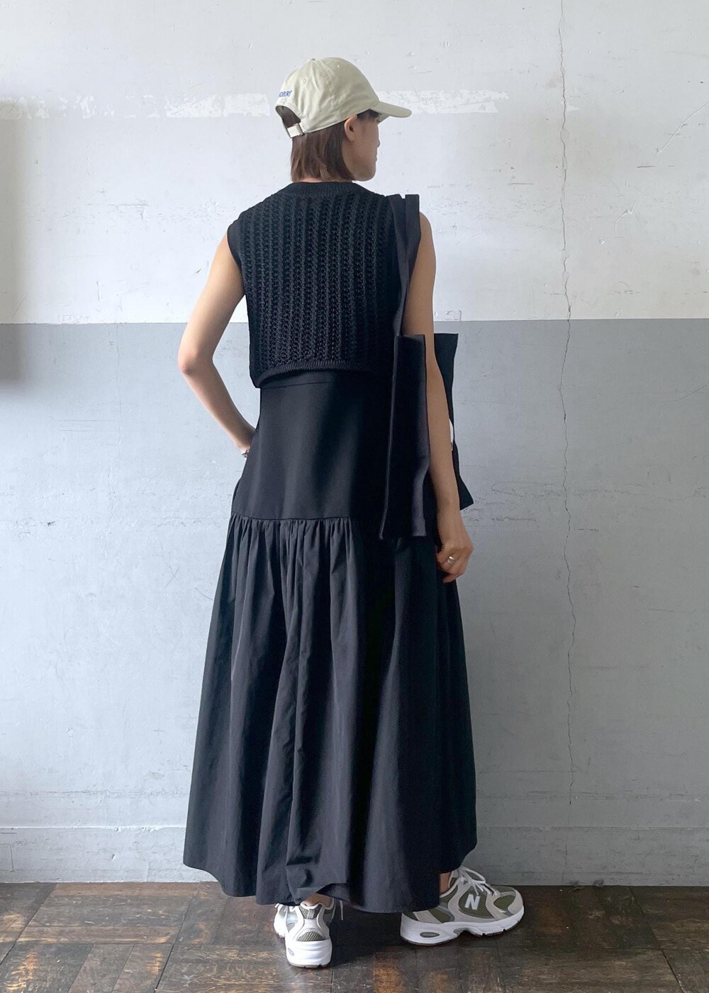 グレー系のスニーカー、ブラック系のワンピース、ブラック系のベストを着用したレディースの夏コーディネートの4枚目の写真