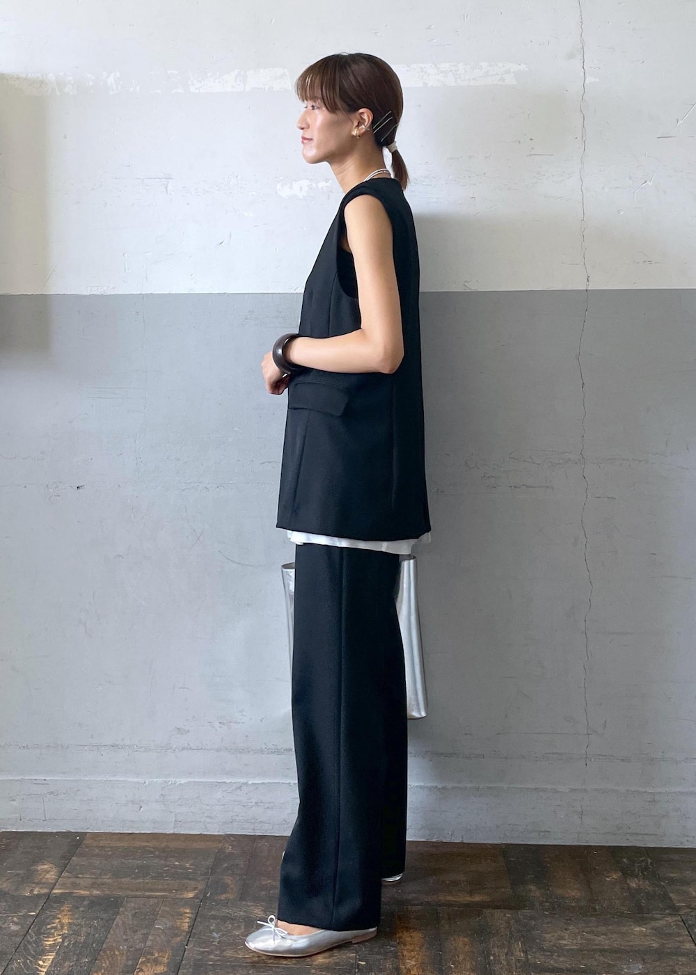 シルバー系のバレエシューズ、シルバー系のトートバッグ、ブラック系のベストを着用したレディースの夏コーディネートの3枚目の写真