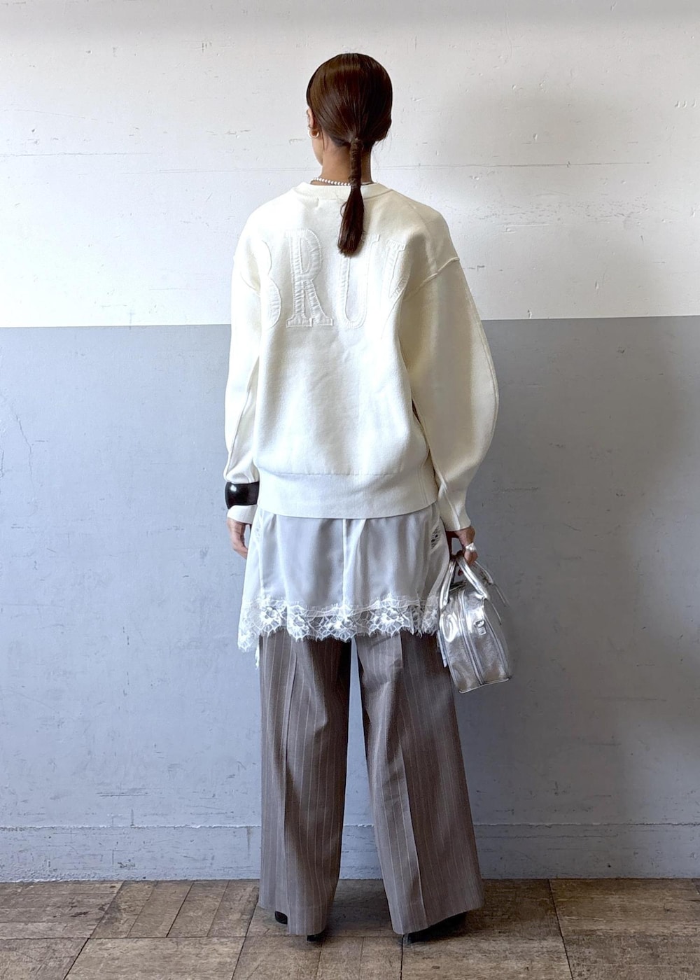 シルバー系のショルダーバッグ、ホワイト系のニット/セーター、ブラック系のブーツを着用したレディースの秋コーディネートの3枚目の写真