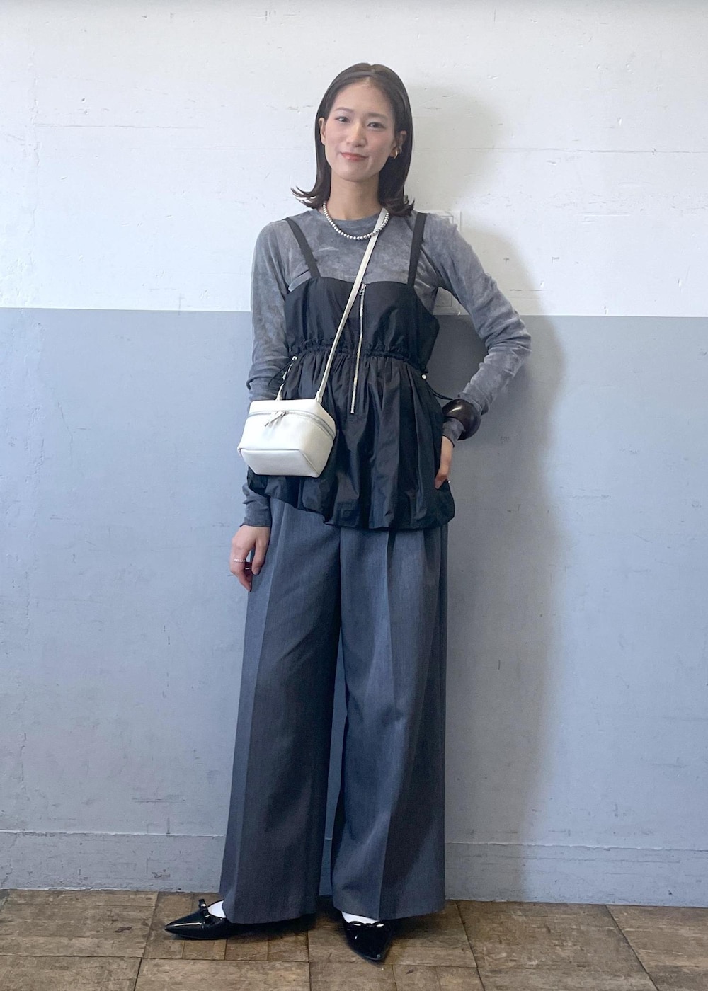 ブラック系のパンプス、グレー系のスラックス、ブラック系のTシャツ/カットソーを着用したレディースの冬コーディネートの2枚目の写真