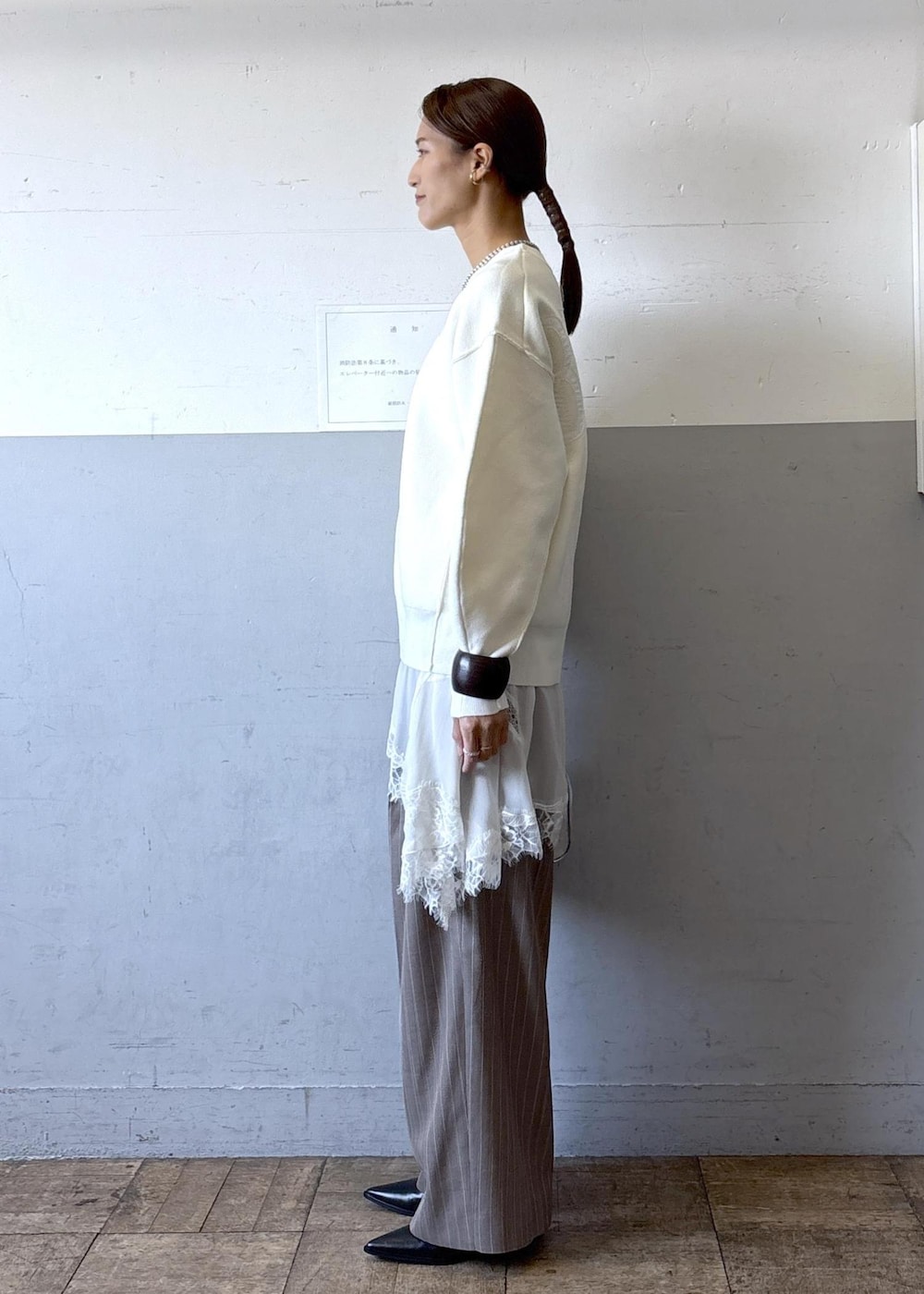 シルバー系のショルダーバッグ、ホワイト系のニット/セーター、ブラック系のブーツを着用したレディースの秋コーディネートの2枚目の写真