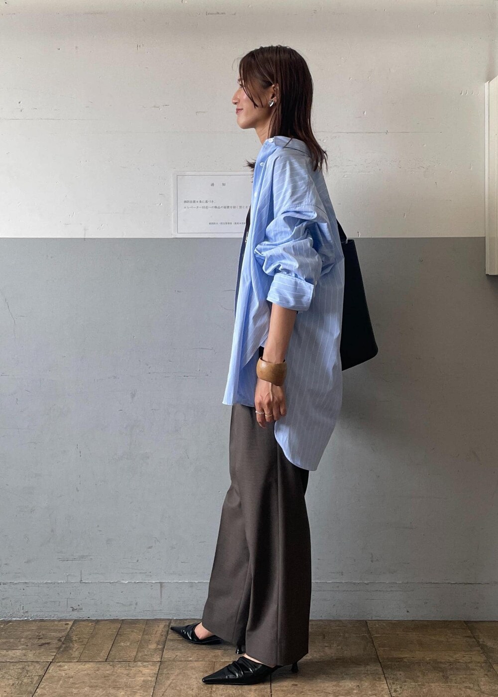 ブラック系のサンダル、ブラック系のショルダーバッグ、グレー系のスラックスを着用したレディースの夏コーディネートの2枚目の写真