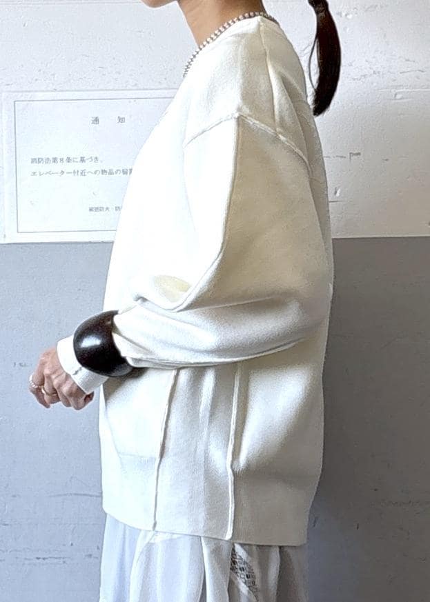 シルバー系のショルダーバッグ、ホワイト系のニット/セーター、ブラック系のブーツを着用したレディースの秋コーディネートの5枚目の写真